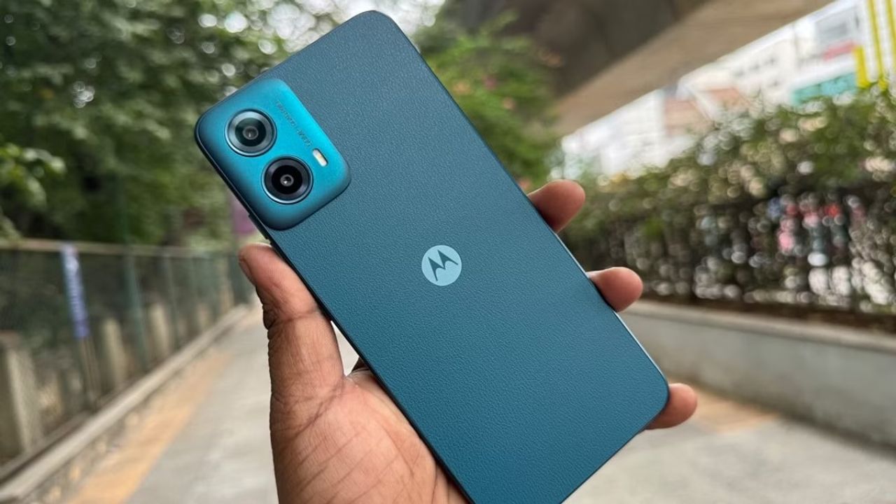 Motorola G34 5G in hand in blue color near some trees