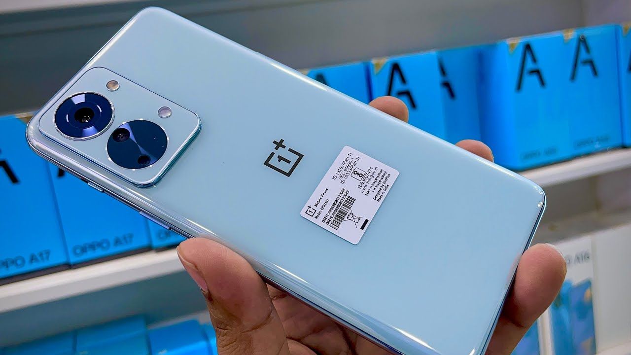 OnePlus Nord 2T 5G in blue color in hand infront of some mobile phone box