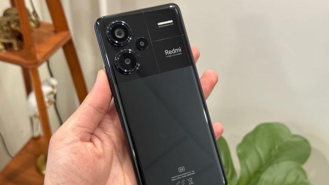 Redmi Note 13 Pro in black color in a hand infront of wall